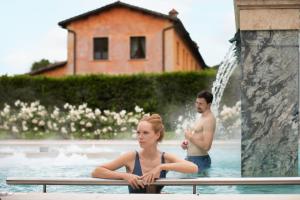 mężczyzna i kobieta siedzący w basenie w obiekcie QC Termeroma Spa and Resort w mieście Fiumicino