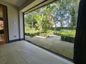 an open glass door with a view of a garden at Modernised seven bedroom country house and garden with hot tub in Cranbrook