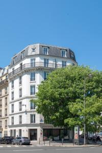 um edifício branco com uma árvore em frente em Hôtel Coypel by Magna Arbor em Paris