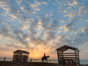 eine Person, die bei Sonnenuntergang auf einem Pferd am Strand reitet in der Unterkunft Caspian Seaside Villa in Sumqayıt