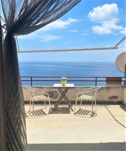 einen Tisch und Stühle auf einem Balkon mit Meerblick in der Unterkunft Casa Lucia in Letojanni