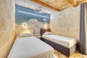 two beds in a room with a painting on the wall at Le Petit Voyage - CHILL OUT in Cospicua