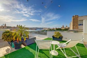 a balcony with two chairs and a table and grass at Le Petit Voyage - CHILL OUT in Cospicua