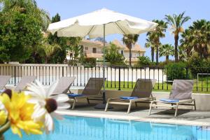 a group of chairs and an umbrella next to a swimming pool at Villa Oceania - Beachfront in Paralimni