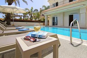 a glass of wine on a table next to a swimming pool at Villa Oceania - Beachfront in Paralimni
