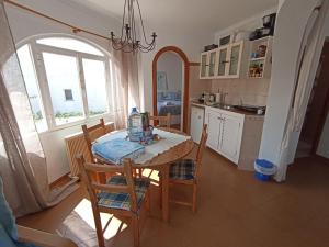 cocina con mesa, sillas y ventana en Casa Joana, en Cala Santanyi
