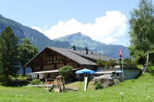 a large wooden building with mountains in the background at Landgasthof Tännler in Innertkirchen