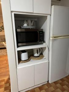 eine Mikrowelle in einem weißen Schrank neben einem Kühlschrank in der Unterkunft Cozy Inn in Perth