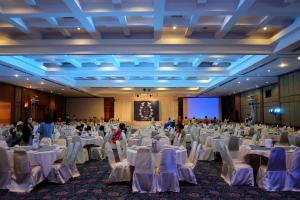 Ubonburi Hotel في أوبون راتشاثاني: قاعة احتفالات كبيرة مع طاولات وكراسي بيضاء