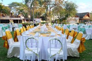 Ubonburi Hotel في أوبون راتشاثاني: تم إعداد طاولة لحضور حفل زفاف مع كراسي صفراء وبيضاء