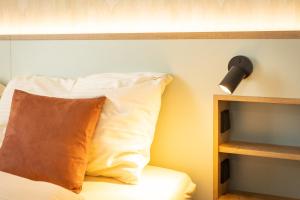 1 cama con almohada y una luz en la pared en Hotel zum Löwen, en Weissenhorn