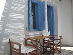una mesa y sillas en un porche con una puerta azul en Maki House, en Anafi