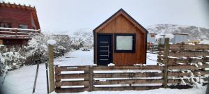 a wooden cabin with a fence in the snow at Patagonia Tiny House in El Chalten