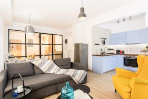 een woonkamer met een bank en een keuken bij Chill in condo next Kalimarmaro! in Athene