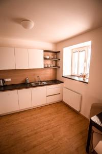 a kitchen with white cabinets and a window at Penzion Panský dvůr Telč in Telč