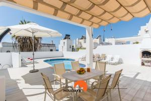 eine Terrasse mit Tisch und Stühlen und einem Sonnenschirm in der Unterkunft #052 V4 Mimosas by Home Holidays in Páteo