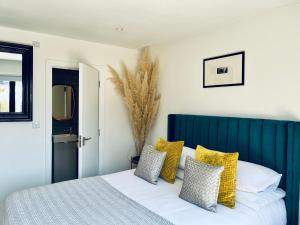 a bedroom with a bed with yellow and white pillows at Beautiful Beach House in Littlestone-on-Sea