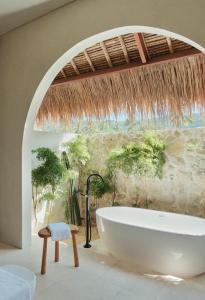 a bathroom with a tub and a stone wall at Boni Beach Lombok Boutique Hotel in Selong Belanak