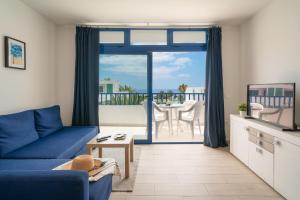 a living room with a blue couch and a balcony at Sabbia Suites Pleamar in Puerto del Carmen