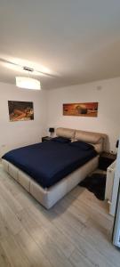 a bedroom with a large bed with a blue blanket at Apartament cu 1 camera spatios ,luminos . in Cugir