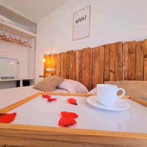 a bed with a table with a cup and red flowers on it at Tabbu ibiza apartments in Playa d'en Bossa