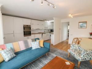 a living room with a blue couch and a kitchen at Sunny Breeze in Kingsbridge