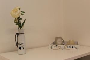 a white vase with a white rose and a clock at All'antico ulivo Affittacamere in Artegna