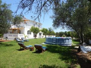 a group of chairs sitting in the grass in front of a house at Villa Alexia in Souda