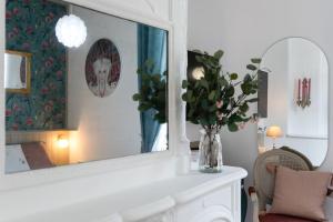 un espejo con un jarrón de flores en una habitación en Pénélope - Charmant Studio Centre Pont-Audemer, en Pont-Audemer
