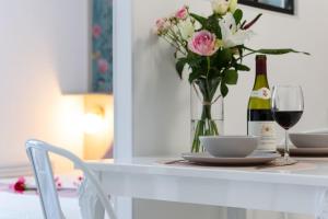 una mesa con un jarrón de flores y una botella de vino en Pénélope - Charmant Studio Centre Pont-Audemer, en Pont-Audemer