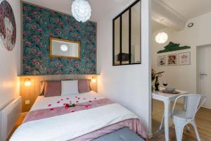 Un dormitorio con una cama y una mesa con flores. en Pénélope - Charmant Studio Centre Pont-Audemer, en Pont-Audemer