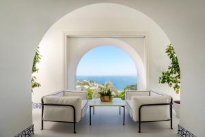 カプリにあるPalazzo M Capriのテーブルと椅子2脚、窓が備わる客室です。