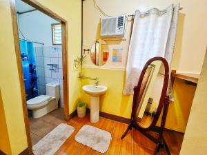 a bathroom with a sink and a toilet and a mirror at Besaga Beachfront B&B - Port Barton in San Vicente