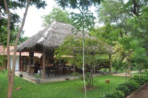 a hut with a grass roof in a garden at Refresh Cabana Gardens in Kataragama