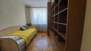 a bedroom with a bed and a book shelf at Економ у центрі 3 кімнати in Luts'k