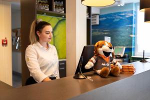 une femme assise à un bureau avec un animal farci dans l'établissement Dormio Resort Eifeler Tor, à Heimbach