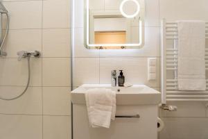 a white bathroom with a sink and a mirror at Bellevue-Haus-B-Wohnung-13 in Großenbrode