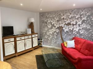 a living room with a red couch and a tree mural at La Mamone in Ornans