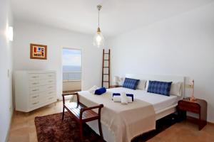 um quarto branco com uma cama e uma cadeira em Villa Can Biel Canyamel by Slow Villas em Canyamel