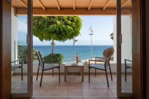 eine Terrasse mit einem Tisch, Stühlen und Meerblick in der Unterkunft Sabbia Suites Sea View La Playita in Puerto del Carmen