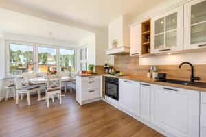 a kitchen with white cabinets and a dining room with a table at Haus TraumAnker in Bresewitz