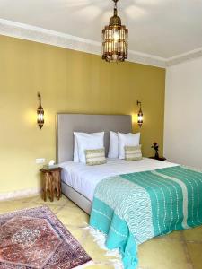 - une chambre avec un grand lit blanc et un lustre dans l'établissement Riad Deha & Spa, à Marrakech
