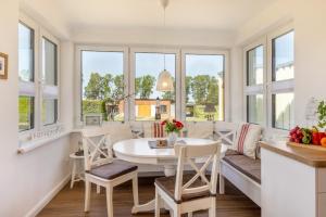 a living room with a table and chairs and windows at Haus TraumAnker in Bresewitz