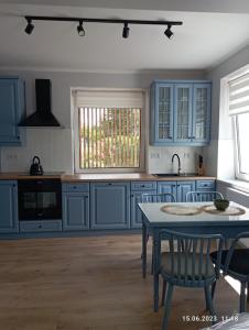 una cocina con armarios azules y una mesa con sillas en STUDIO 102, en Bachowice