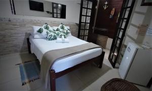 a bedroom with a bed with white sheets and green pillows at Pousada Refugio do Pirata in Trindade