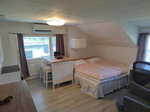 Habitación pequeña con cama y escritorio. en Kalle's unluxury guest house Aircon 15min city center by train en Helsinki