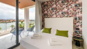 een wit bed in een kamer met een groot raam bij Welcomely - Affittacamere Seamphony Rooms in Olbia