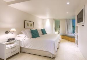 a bedroom with a large white bed with green pillows at Abracadabra Pousada in Búzios