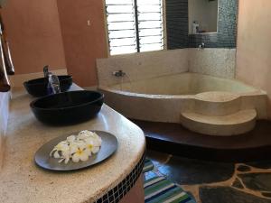 un baño con bañera y un plato de flores en una encimera en Wagawimbi Villa 560 m2, Breathtaking View of the Indian Ocean, Kenya, en Shimoni