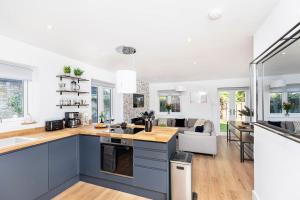 a kitchen with blue cabinets and a living room at Gorgeous SeaHaze sleeps 8 new forest +bikes/chef in Everton